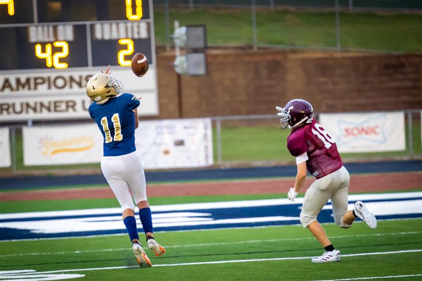 An Independence High player jumps to catch the football at the end zone